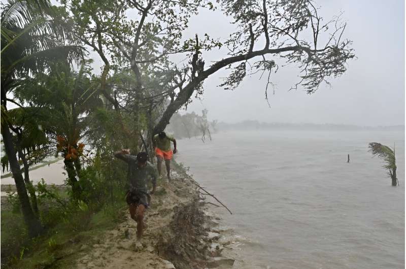 People walk on a damaged embankment during heavy rains in Patuakhali in May 2024, after Cyclone Remal made landfall