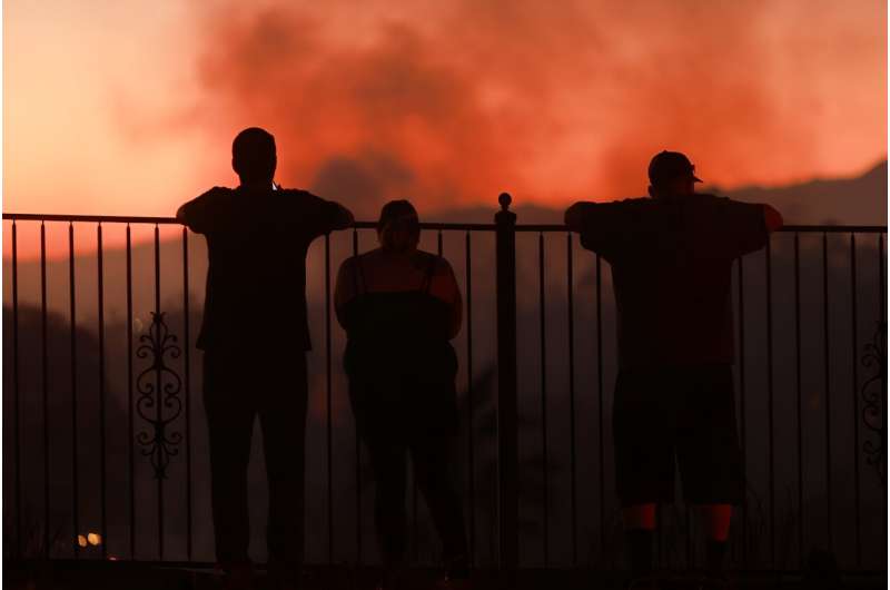 People watch as a wildfire burns close to properties in Riverside, California, on July 21, 2024
