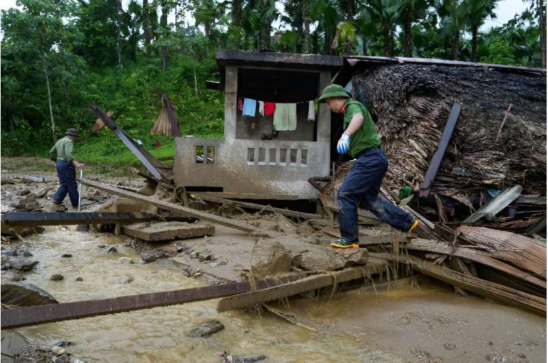 Police officers inspect a house after a landslide engulfed a remote mountainous village in Vietnam's Lao Cai province