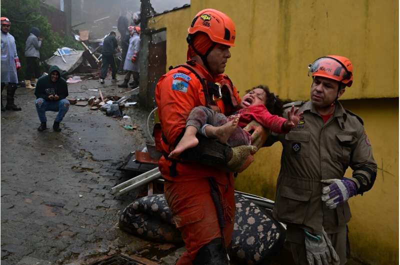 Rescuers carry a girl, who had been trapped for hours  under the rubble of her house that was destroyed by heavy rains in Petropolis, Brazil, on March 23, 2024