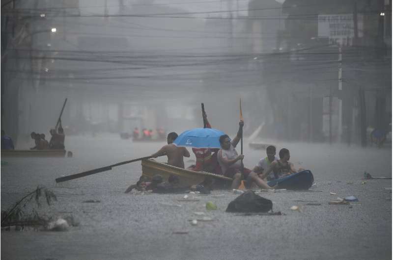 Rescuers paddle boats along a flooded street in Manila following heavy rains brought by Typhoon Gaemi