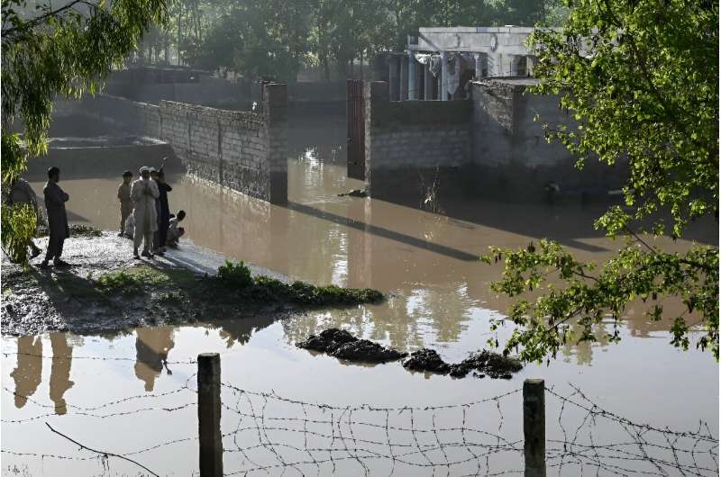 Residents stand outside their flooded homes following heavy rains in Charsadda district of Khyber Pakhtunkhwa province on April 17, 2024