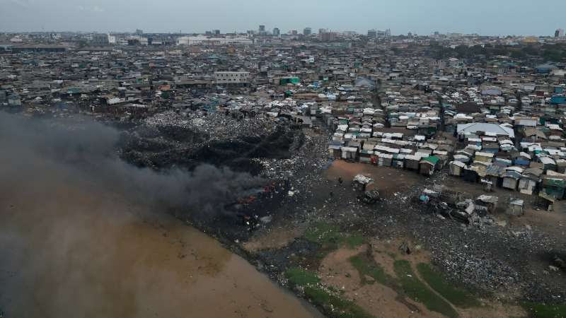 Smoke rises from a water-side dump of discarded clothes in Accra, Ghana