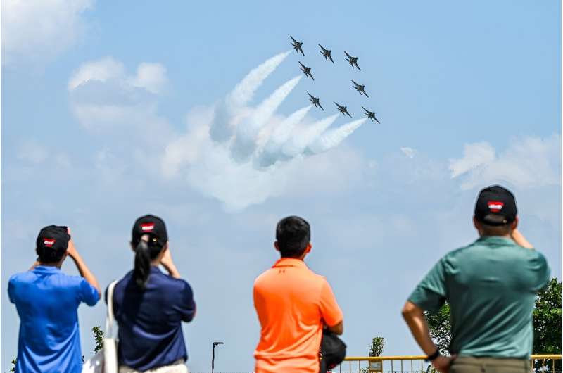 Spectators watch members of South Korea's 'Black Eagle' aerobatics team performing during a preview of the Singapore Airshow in Singapore on February 18, 2024
