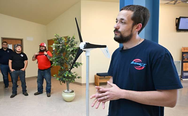 Student-turned-instructor Nathaniel Alexander speaks beside a mini replica of a wind turbine on the campus of Mesalands Community College in the former Route 66 town of Tucumcari, New Mexico on July 11, 2024