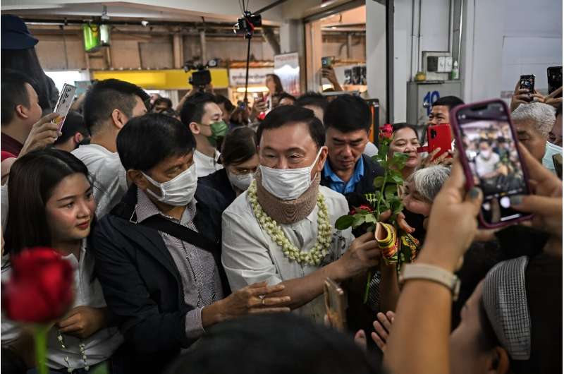 Thailand's former prime minister Thaksin Shinawatra visits a Chiang Mai market, donning a face mask while posing for photos with well-wishers