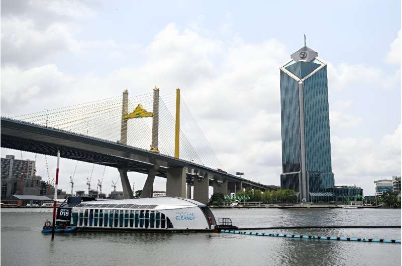 The boat-like structure uses the river current to funnel plastic into the barge's waiting jaws