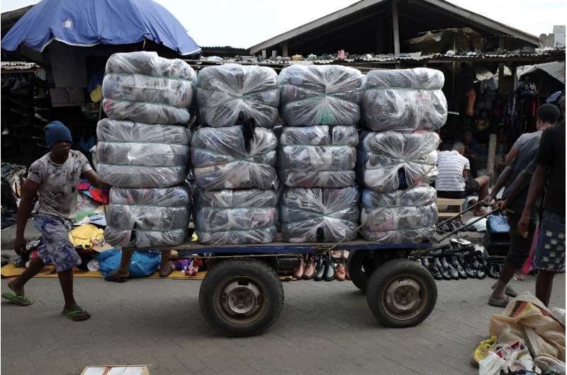 Traders push a trolley with bales of secondhand clothes through Kantamanto market in Accra, Ghana