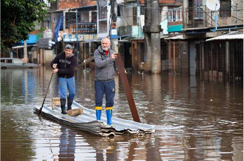 Two men paddle a canoe made of zinc tiles and styrofoam down a flooded street in the Vila Farrapos neighborhood in Porto Alegre, Brazil, on May 29, 2024