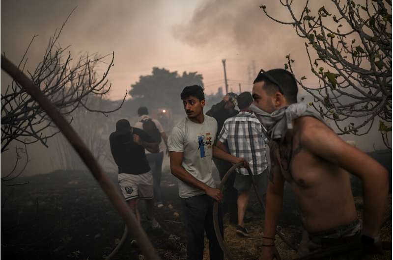 Volunteers try to extinguish a wildfire northeast of Athens that has forced the evacuation of thousands of people in suburban towns