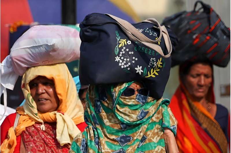 Women shelter from the sun as they walk along a street on a hot summer day in India's city of Varanasi