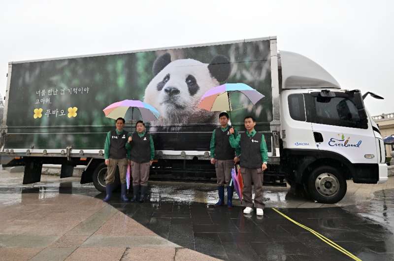 Zookeepers pose for photos in front of a vibration-free special vehicle carrying giant panda Fu Bao