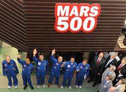 Members of the Mars 500 crew wave before being locked into the isolation facility in Moscow
