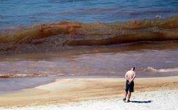 A beachgoer looks at oil in the water on Orange Beach, Alabama in June