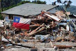 A Chilean flag flutters next to a destroyed house in Constitucion