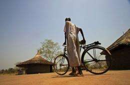 A displaced Sudanese man pushes his bike through Malou village in southern Sudan's Lakes State