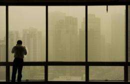 A man stands by windows as a sandstorm hits Beijing