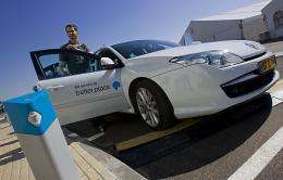 An Israeli man stops an electric car next to a charging station at the first electric vehicle demonstration centre