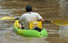 A resident paddles a kayak loaded with XXXX beer back to his flooded home in Rockhampton