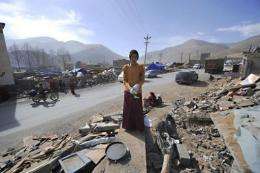 A Tibetan Buddhist monk puts on gloves as he cleans up rubble
