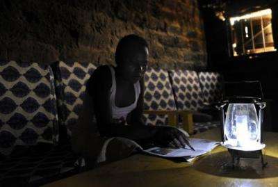 A villager at Chumbi village, some 50 km southeast of Nairobi, reads with the aid of a solar-powered lamp