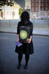 A woman carries a 'BP oil barrel' during a protest by artists calling themselves 'The Good Crude Britannia'