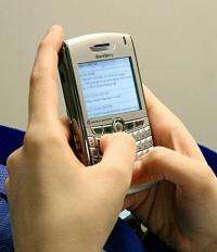 A woman sends text messages on her Blackberry phone
