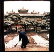 A woman sweeps snow off the steps of a temple in Beijing