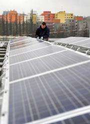 A worker adjusts the solar panels on the roof of the Max-Schmeling-Halle in Berlin