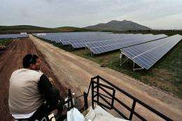 A worker looks on as he rests in a solar farm in Thiva
