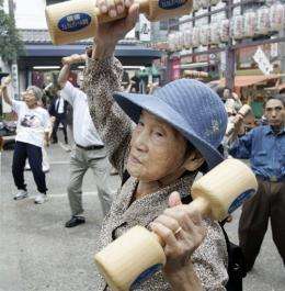 Elderly people work out with wooden dumb-bells at a temple in Tokyo
