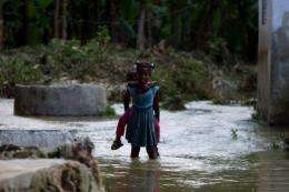 Haitian children walk in floodwaters in Leogane, 60kms south of Port-au-Prince