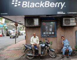 Indian men chat outside a BlackBerry phone store in Mumbai
