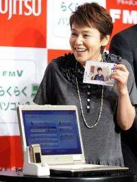Japanese actress Shinobu Otake displays a notebook PC for senior citizens