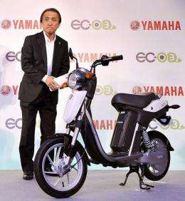 Japan's Yamaha Motor President Hiroyuki Yanagi stands next to the company's new electric commuter vehicle EC-03