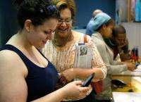 Local resident Susan Linsky (2nd L) watches as her daughter Arielle (L) tries out the Palm Pre smartphone