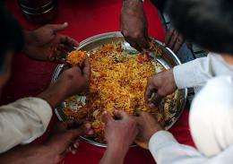 Poverty stricken Pakistani people eat free food outside a charitable organizations office in Karachi