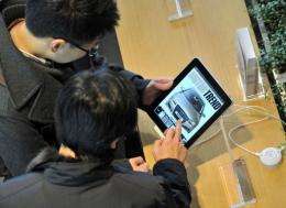 South Korean men look at Apple's iPad at a KT shop during its launch in Seoul