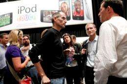 Steve Jobs (C), chief executive officer of Apple Inc., speaks to reporters