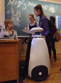 Students speak with their teacher near Stepan the robot