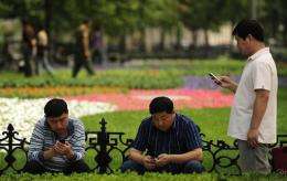Three men use their mobile phones on a street in Beijing