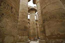 Tourists explore stone columns decorated with hieroglyphs at the Karnak temple site in Luxor