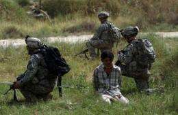 US soldiers guard a detained Iraqi suspected of ties to Al-Qaeda on the southern outskirts of Baghdad, in 2007