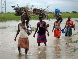Women wade through water covering the street near the Limpopo river, Mozambique, in January