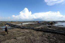 Workers attempt to control the flow of mud from the Lapindo mud volcano