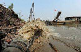 Workers go about their chores near the collapsed bank of the Huai river