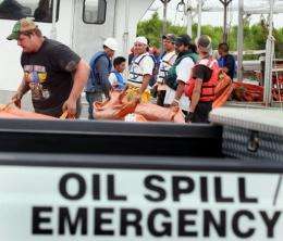 Workers load oil booms onto a boat as the effort continues to try and contain the massive oil spill
